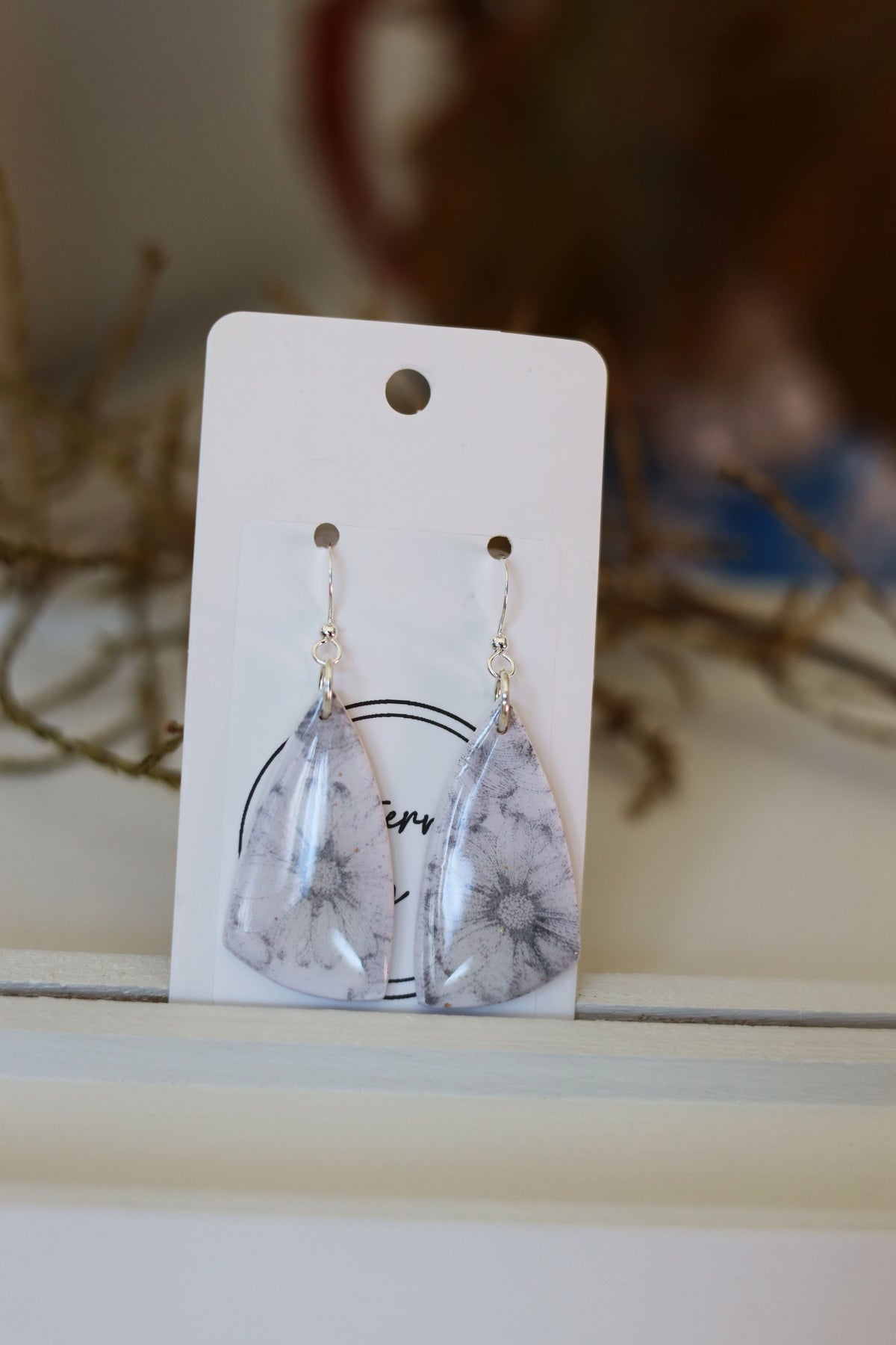White dangle earrings with grey floral pattern
