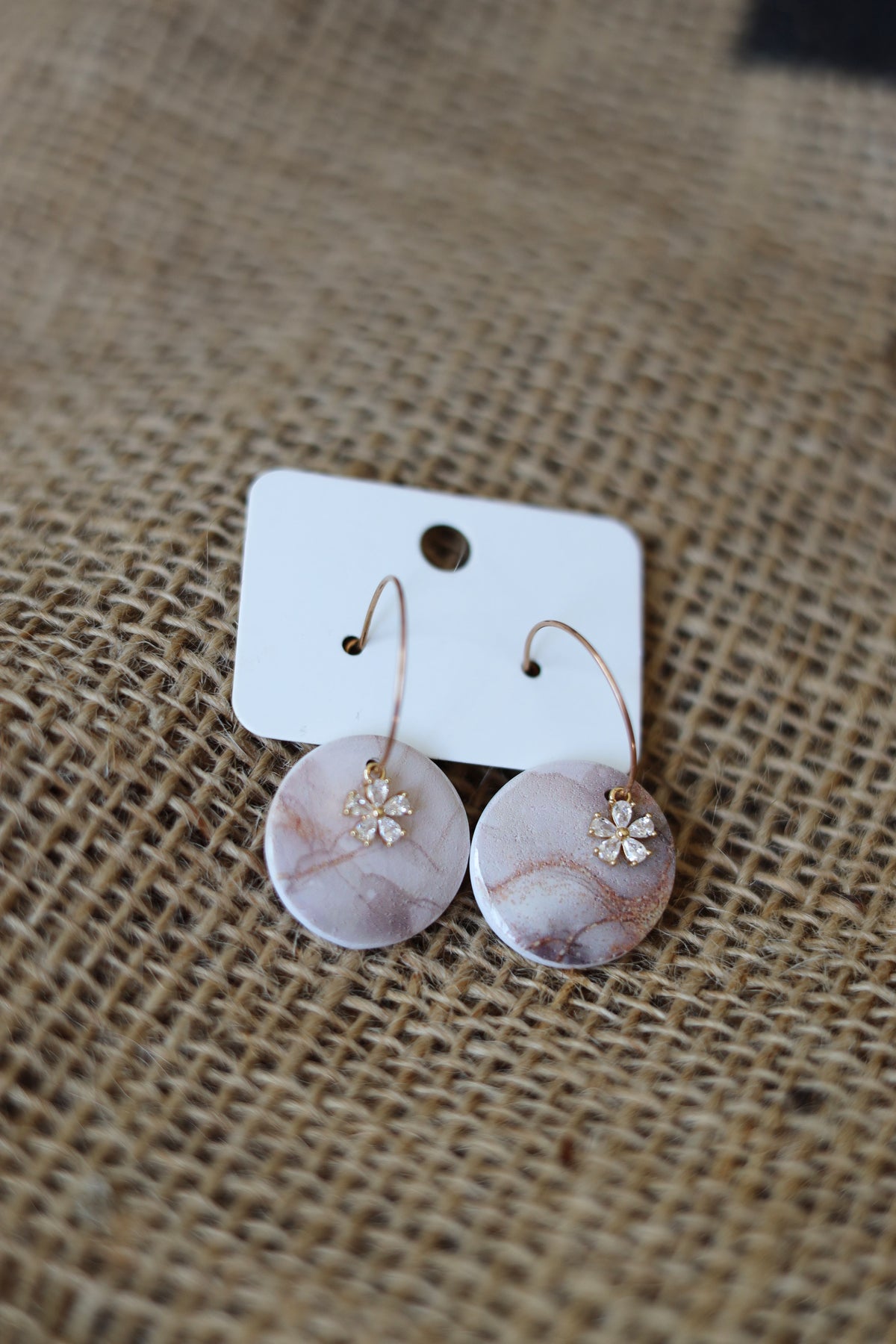 Abstract designed hoop earrings with rhinestone flower.